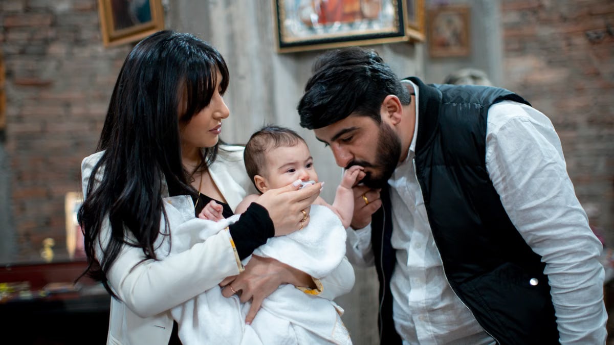 A family with a baby enjoying a heartfelt moment during a religious ceremony indoors.
